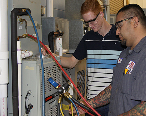 Two students working on AC unit