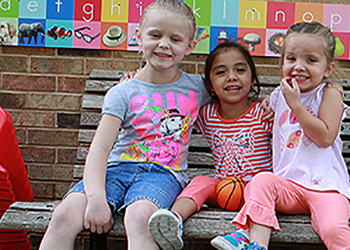 Children enjoying playground bench together