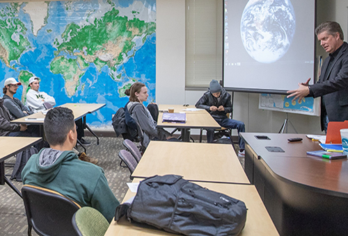 Geography/Global Studies instructor speaking to students in the classroom